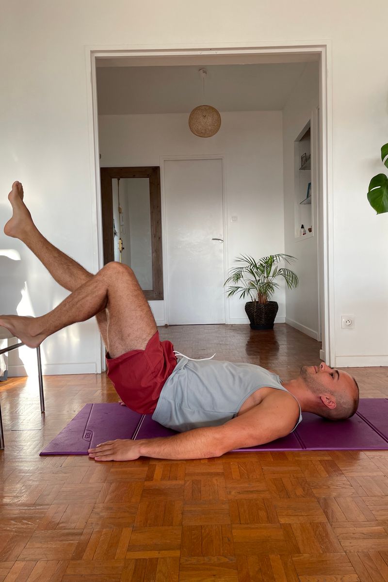 A man doing a leg-raise exercise on a mat in his apartment.